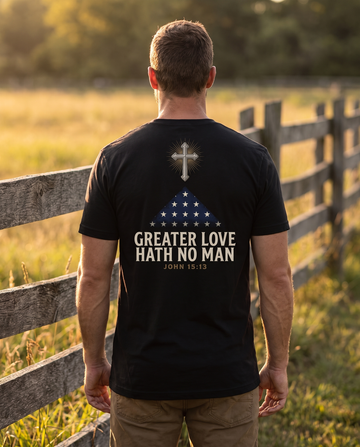 Man seen from behind wearing the tee: radiant cross above a folded memorial flag over GREATER LOVE HATH NO MAN, John 15:13