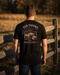 Man seen from behind in a black tee whose back print shows the Tun Tavern sign with cask, lantern and drum, November 10, 1775 &mdash; view 1