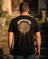 Man seen from behind wearing the North American Martyrs shirt: rope-bound wooden cross, martyrs' palms, Auriesville 1646 &mdash; view 1