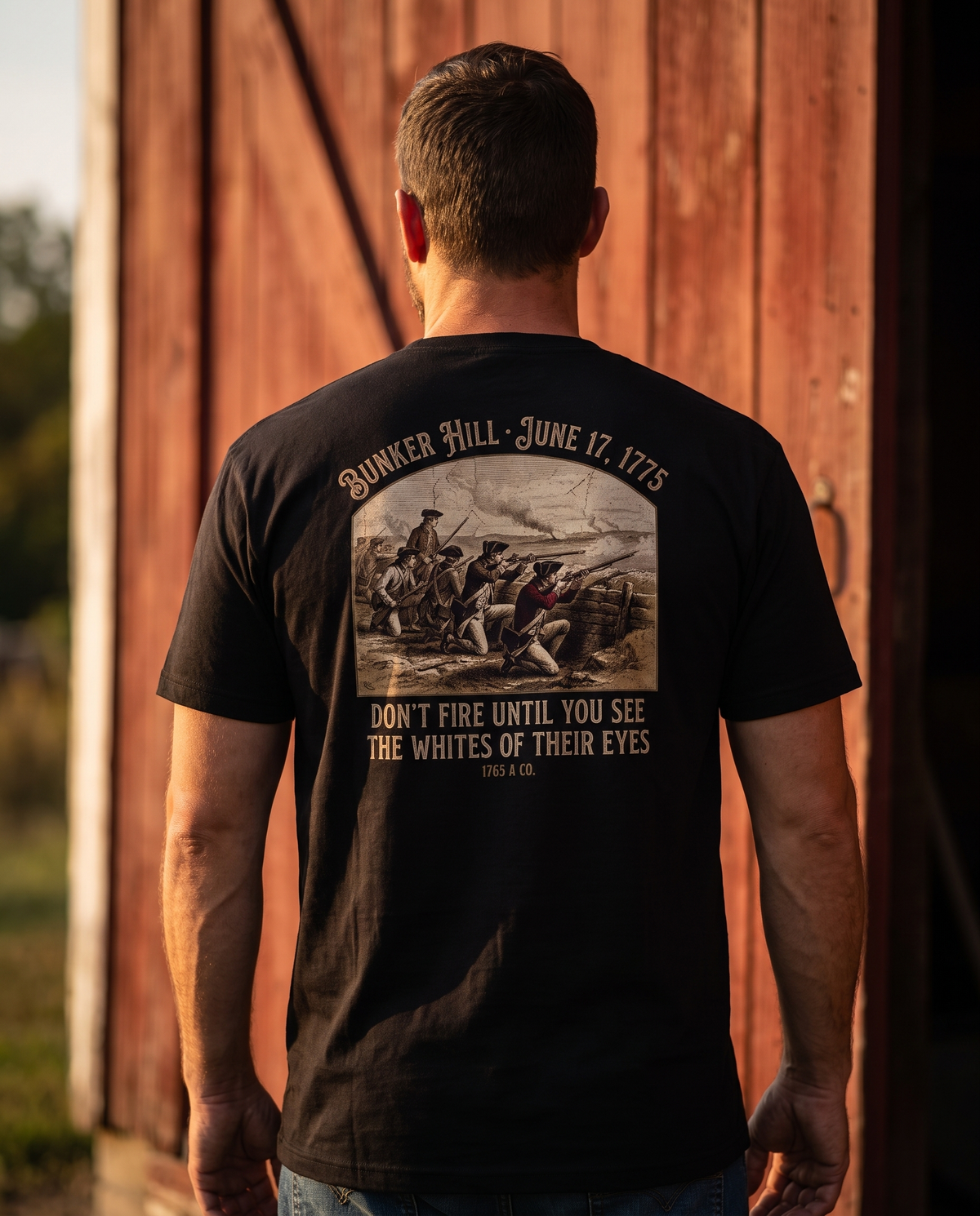 Man seen from behind in the tee: militiamen at a breastwork over 'Don't Fire Until You See the Whites of Their Eyes'
