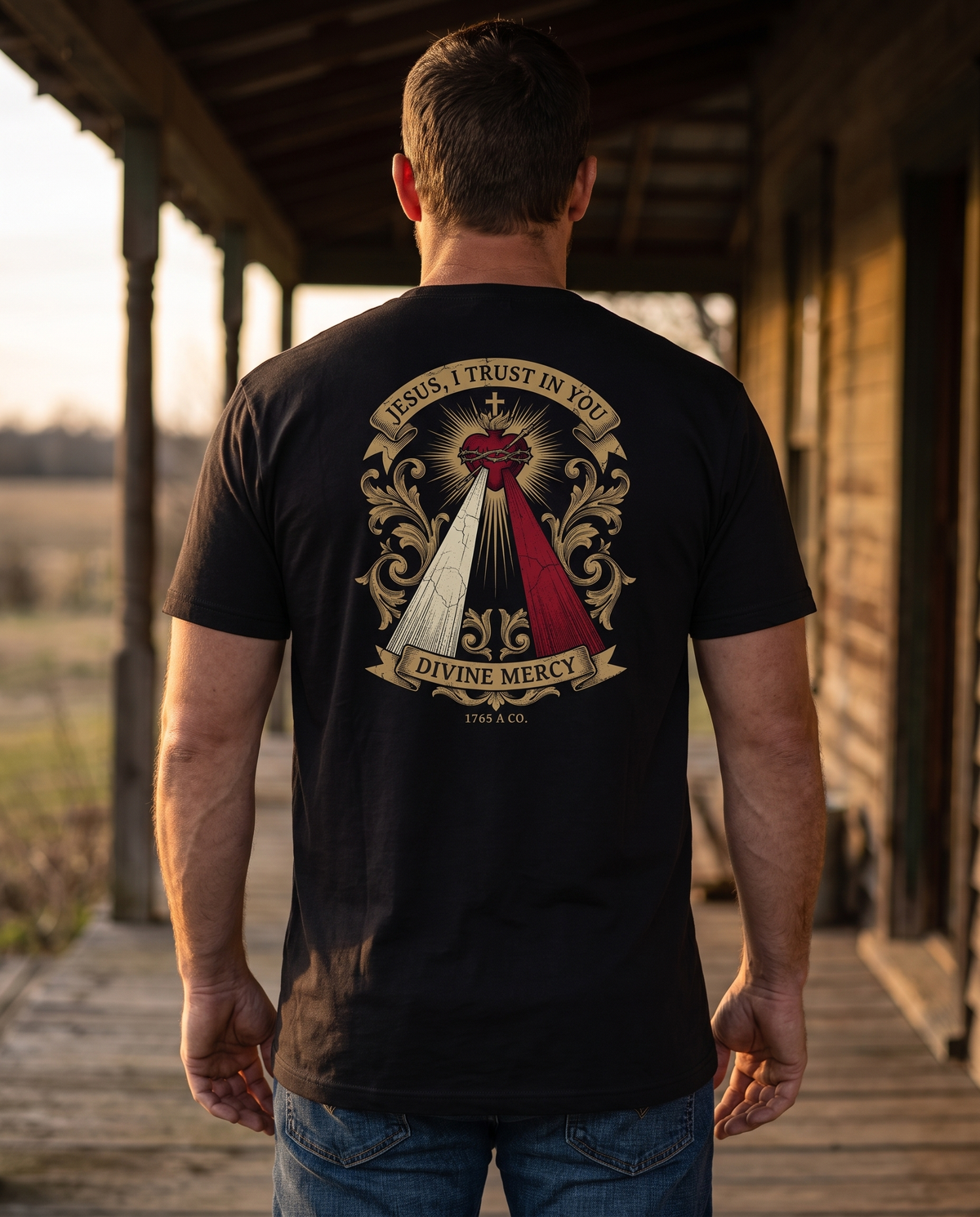 Man seen from behind wearing the tee: the pierced Heart pouring pale and red rays under 'Jesus, I Trust in You'