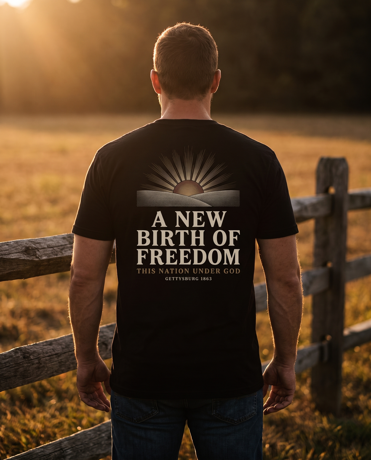 Man seen from behind wearing the tee: engraved sun over rolling fields above A NEW BIRTH OF FREEDOM, Gettysburg 1863