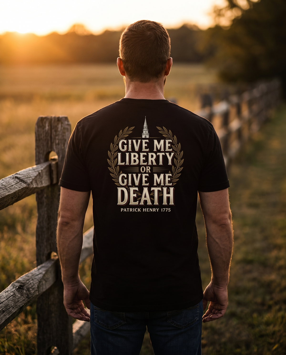 Man seen from behind wearing the Give Me Liberty shirt: bold lettering, gold laurel, church steeple, Patrick Henry 1775