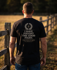 Man seen from behind wearing the tee: small gold cross in a wreath over I HAVE FOUGHT THE GOOD FIGHT, 2 Timothy 4:7 &mdash; view 1