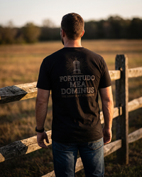 Man seen from behind in a tee whose back print shows a radiant stone tower over FORTITUDO MEA DOMINUS &mdash; view 1