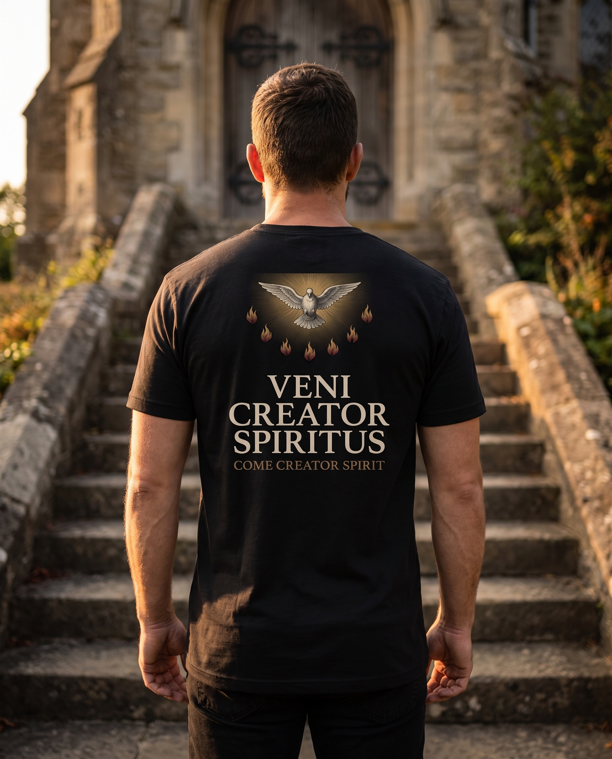 Man seen from behind in a 1765 Apparel tee; back print: a white dove in gold light above seven flames, Veni Creator Spiritus