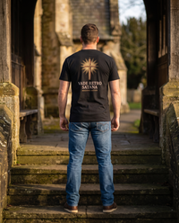 Man seen from behind in a tee whose back print shows an engraved cross in golden rays over VADE RETRO SATANA &mdash; view 1
