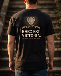 Man seen from behind in a tee whose back print shows a cross in a laurel wreath over a broken chain and HAEC EST VICTORIA &mdash; view 1